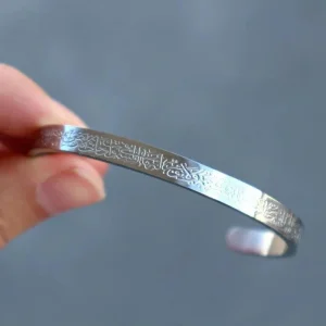 Likely gold-plated metal; laser-etched Arabic calligraphy